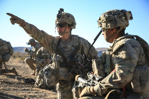 Two military service members with one pointing toward equipment