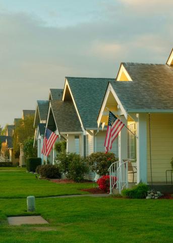 Row of uniform single-family suburban homes with American flags displayed on their front porches.